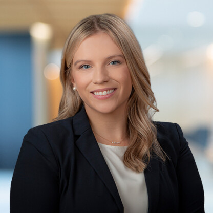A woman with blonde hair wearing a black blazer and white top, smiling, posed in a modern law office setting—perfectly capturing the professionalism of Chicago lawyers.