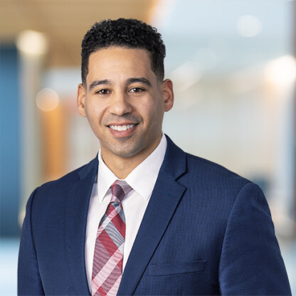 A man in a blue suit, white shirt, and red patterned tie is standing and smiling in a brightly lit, modern law office, reflecting the professionalism of Chicago lawyers.