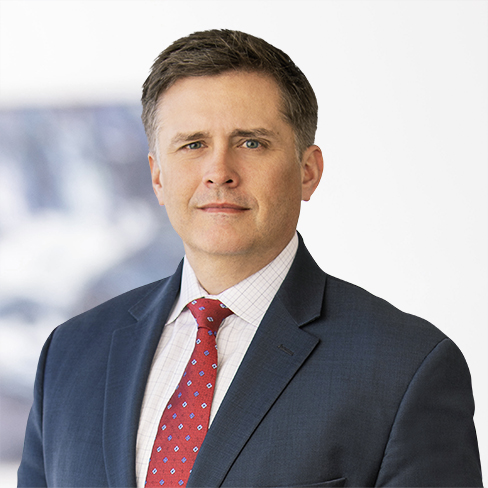 A man in a blue suit, white shirt, and red tie stands in front of a blurred background, facing the camera with a neutral expression—evoking the professionalism of top lawyers in Chicago.