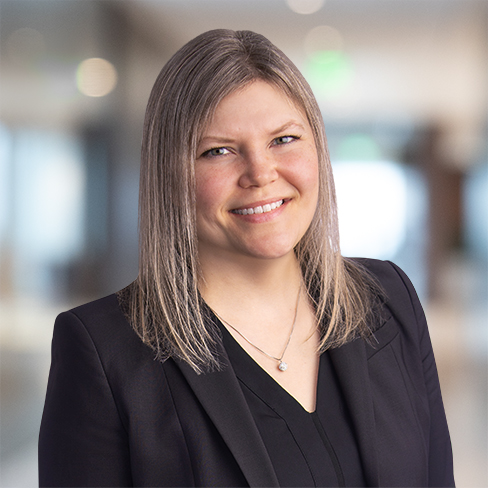 Woman with straight, shoulder-length blonde hair wearing a black blazer and necklace, smiling in a blurred law offices setting—perfect for showcasing litigation support professionals or Chicago lawyers.