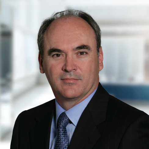 A middle-aged man in a suit and tie poses for a professional headshot against a blurred office background, reflecting the polished image of experienced Chicago lawyers in a corporate law office.