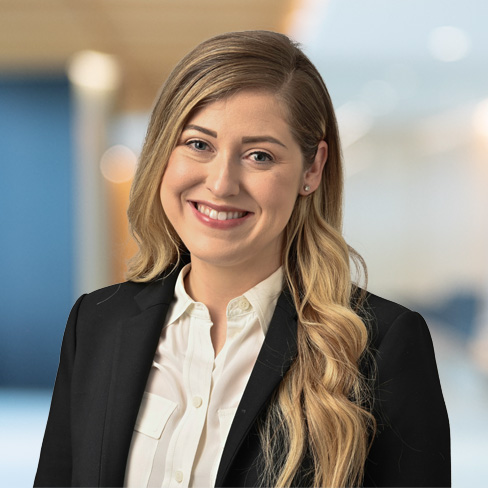 Woman with long blonde hair wearing a black blazer and white shirt, smiling at the camera in a corporate law office, showcasing litigation support professionals and lawyers in Chicago.