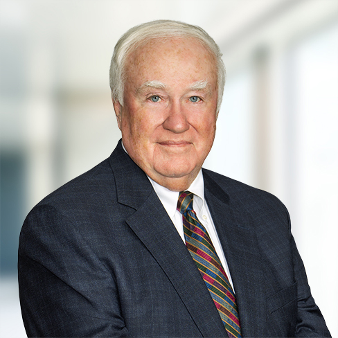 An older man with short white hair wearing a dark suit, white shirt, and striped tie stands in front of a blurred office background, reflecting the professionalism of top law offices and lawyers in Chicago.