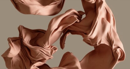 Wrinkled, light-brown fabric pieces are suspended in mid-air against a plain beige background, evoking the meticulous organization often found in a corporate law office.