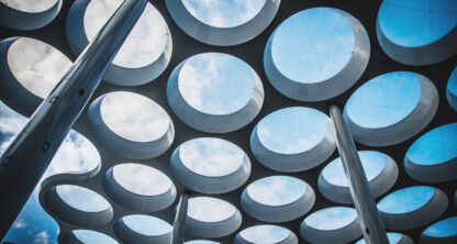 Modern architectural roof structure with circular openings and tall metal columns, viewed from below against a partly cloudy sky—perfect for contemporary law offices or a corporate law office in Chicago.