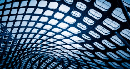 Curved architectural ceiling structure with a grid pattern of square openings, viewed from below at a corporate law office, letting light filter through.