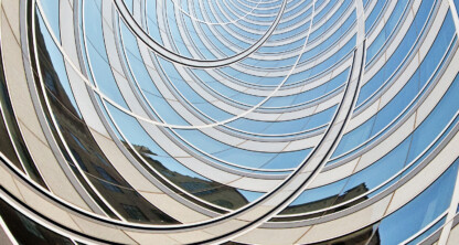 A close-up view of a modern glass building with curved, concentric architectural lines reflects the blue sky—an iconic location for a corporate law office or Chicago lawyers specializing in litigation support.