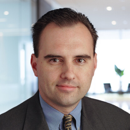 A man in a suit and tie poses for a professional headshot in a modern law offices setting, reflecting the polished image of Chicago lawyers.