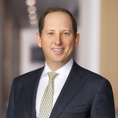 A man in a dark suit and patterned tie stands smiling in a blurred office hallway, representing lawyers in Chicago who specialize in litigation support.