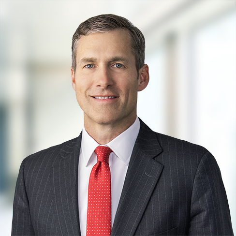 A man in a dark pinstripe suit, white shirt, and red tie stands in a brightly lit, modern corporate law office, reflecting the professional atmosphere of top Chicago lawyers.
