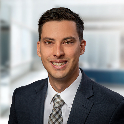 A man in a dark suit, white shirt, and patterned tie smiles at the camera in a brightly lit law office, reflecting the professionalism of lawyers in Chicago.