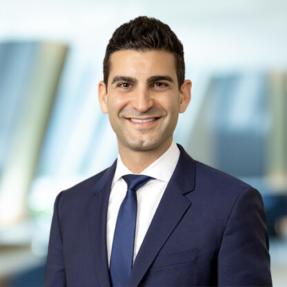 A man in a navy suit and tie smiles while standing in front of a blurred office background, representing chicago lawyers who specialize in litigation support.