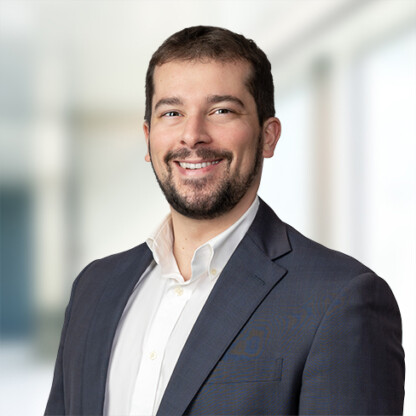 A man in a dark suit jacket and white shirt smiles at the camera against a blurred indoor background, reflecting the professionalism of top lawyers in Chicago.