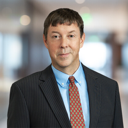 A man in a pinstripe suit, blue shirt, and patterned red tie poses for a professional headshot in an office setting, reflecting the polished image of lawyers in Chicago.