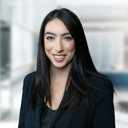 A woman with long dark hair, wearing a black blazer, smiles at the camera in a modern, bright corporate law office—ideal for those seeking experienced Chicago lawyers.