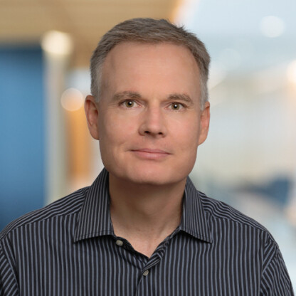 A middle-aged man with short gray hair wearing a black and white striped shirt, posed in a law offices setting with a blurred background, reflecting the professional atmosphere of Chicago lawyers.