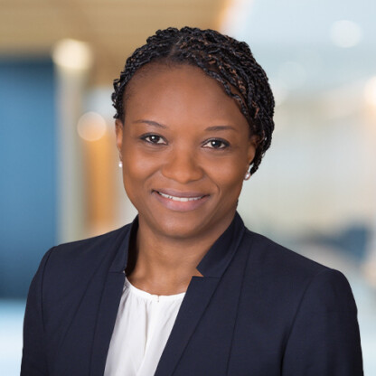 A woman in business attire with braided hair smiles at the camera in a law office, reflecting the professionalism of Chicago lawyers.