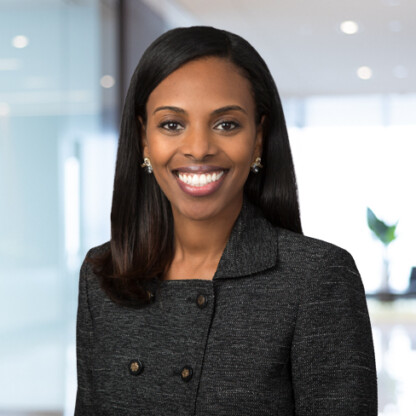 A woman in a dark blazer smiles at the camera in a brightly lit, modern corporate law office, exemplifying the professionalism of Chicago lawyers.