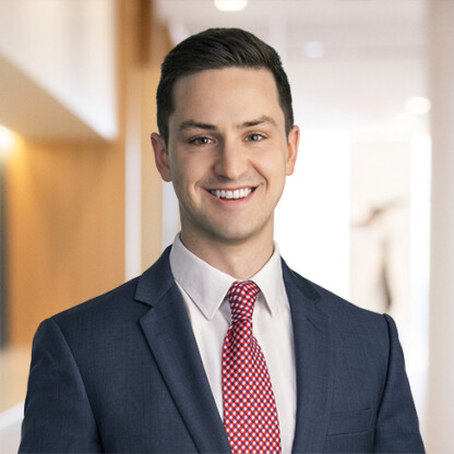 A man in a navy suit, white shirt, and red patterned tie is smiling in a brightly lit law office hallway, embodying the professionalism of Chicago lawyers.