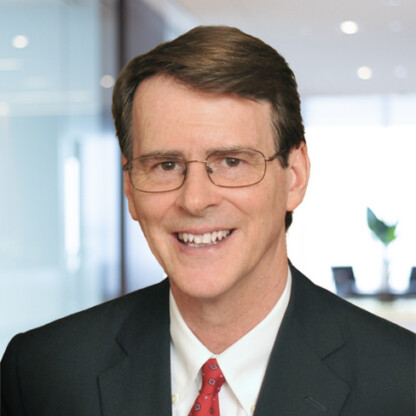 A man wearing glasses, a dark suit, white shirt, and red tie smiles in an office setting with glass walls—reflecting the professionalism of top lawyers in Chicago.