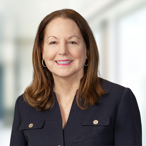 A woman with long brown hair, wearing a dark blazer and hoop earrings, smiles at the camera in a brightly lit law office, reflecting the professionalism of Chicago lawyers.