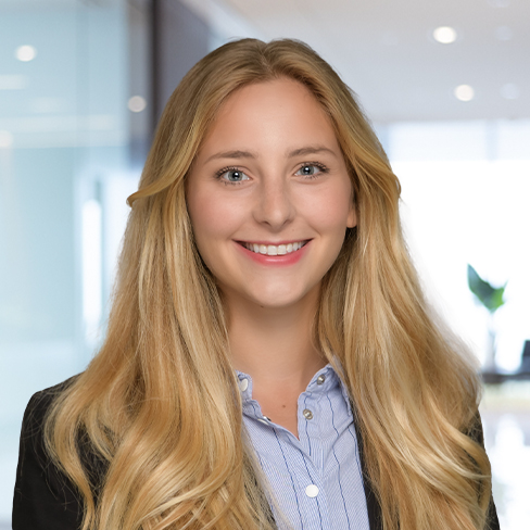 A woman with long blonde hair, wearing a black blazer and striped shirt, smiles at the camera in a modern office—reflecting the professionalism of lawyers in Chicago.