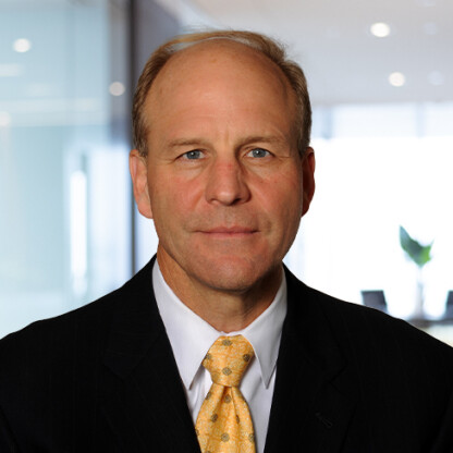 Middle-aged man in a dark suit, white shirt, and yellow tie, posing for a professional headshot in a modern office—ideal for lawyers in Chicago or professionals specializing in intellectual property law.
