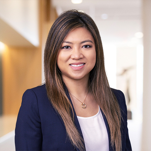 A woman with straight, long brown hair wearing a navy blazer and white top, standing in a modern, well-lit office—reflecting the professionalism and confidence of top lawyers in Chicago.