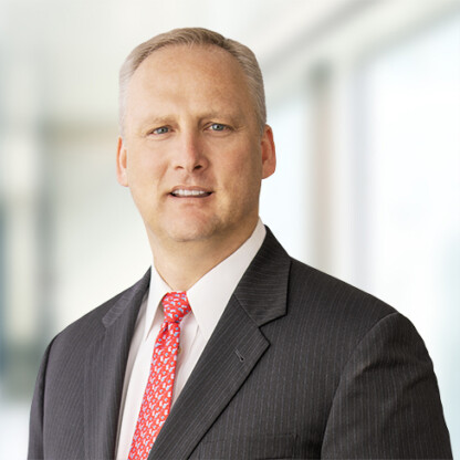 A man in a dark pinstripe suit, white shirt, and red patterned tie stands in front of a blurred office background, reflecting the professionalism of top lawyers in Chicago.