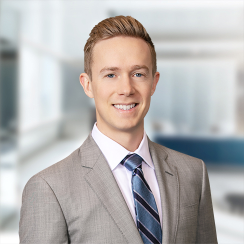 A young man in a light gray suit and striped tie stands smiling in a modern, bright corporate law office, reflecting the professional atmosphere of top lawyers in Chicago.