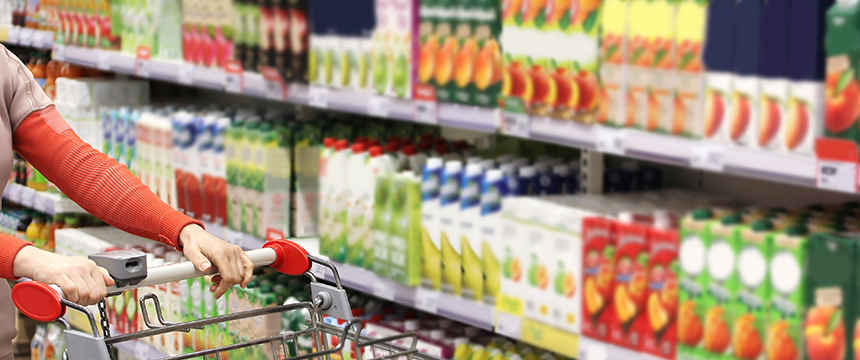Person pushing a shopping cart in a grocery store aisle stocked with various juice cartons and beverages, much like lawyers in Chicago navigating options to provide clients with litigation support.