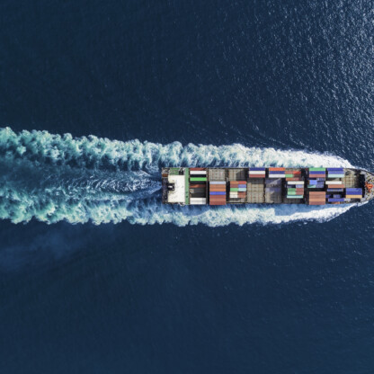 Aerial view of a cargo ship with multicolored containers sailing in blue ocean water, leaving a visible wake—much like how lawyers in Chicago navigate complex cases with precision and expertise.