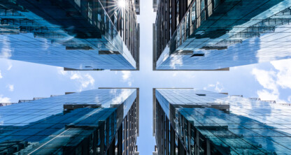 View looking up between four modern glass-clad skyscrapers, with reflections of the sky and sun—an impressive backdrop befitting top Chicago lawyers or a leading corporate law office.