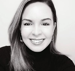 A woman with straight, shoulder-length hair smiles at the camera, wearing a dark turtleneck and hoop earrings, against a plain light background—perfect for a profile in a corporate law office or among respected Chicago lawyers.