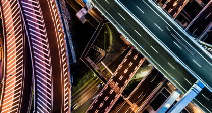 Aerial view of intersecting highways and ramps at night, with marked lanes, streetlights, vehicles on the roads, and the city skyline hinting at the bustling offices of Chicago lawyers nearby.