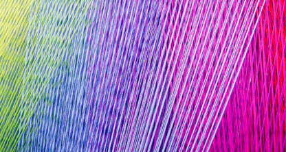 Close-up of colorful threads arranged diagonally, transitioning from yellow and green on the left to blue, purple, and pink on the right—capturing the vibrant diversity found in a busy intellectual property law office.