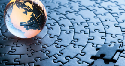 A glass globe rests on a completed circular jigsaw puzzle with one piece missing in the foreground, evoking the intricate problem-solving and precision of a top corporate law office.