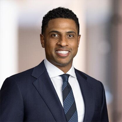 A man in a navy suit, white shirt, and striped tie poses for a professional headshot against a blurred office background, embodying the polished image of leading lawyers in Chicago.