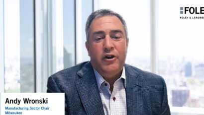 A man in a plaid jacket speaks in an office with large windows, representing Foley & Lardner LLP. Text on screen reads “Andy Wronski, Manufacturing Sector Chair, Milwaukee,” highlighting insights from leading law offices.
