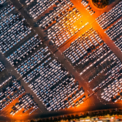 Aerial view of a large parking lot filled with hundreds of parked cars, illuminated by streetlights at night—perhaps belonging to law offices or lawyers in Chicago working late downtown.