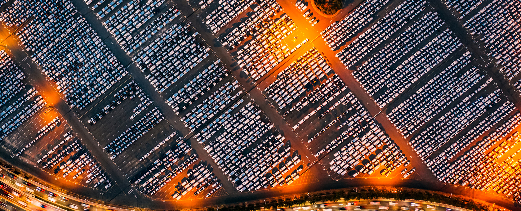 Aerial view of a large parking lot filled with hundreds of parked cars, illuminated by streetlights at night—perhaps belonging to law offices or lawyers in Chicago working late downtown.