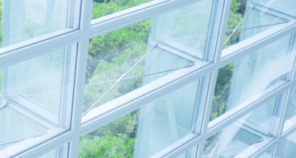 Large glass windows with metal frames provide a view of green trees outside, allowing natural light to enter the corporate law office.