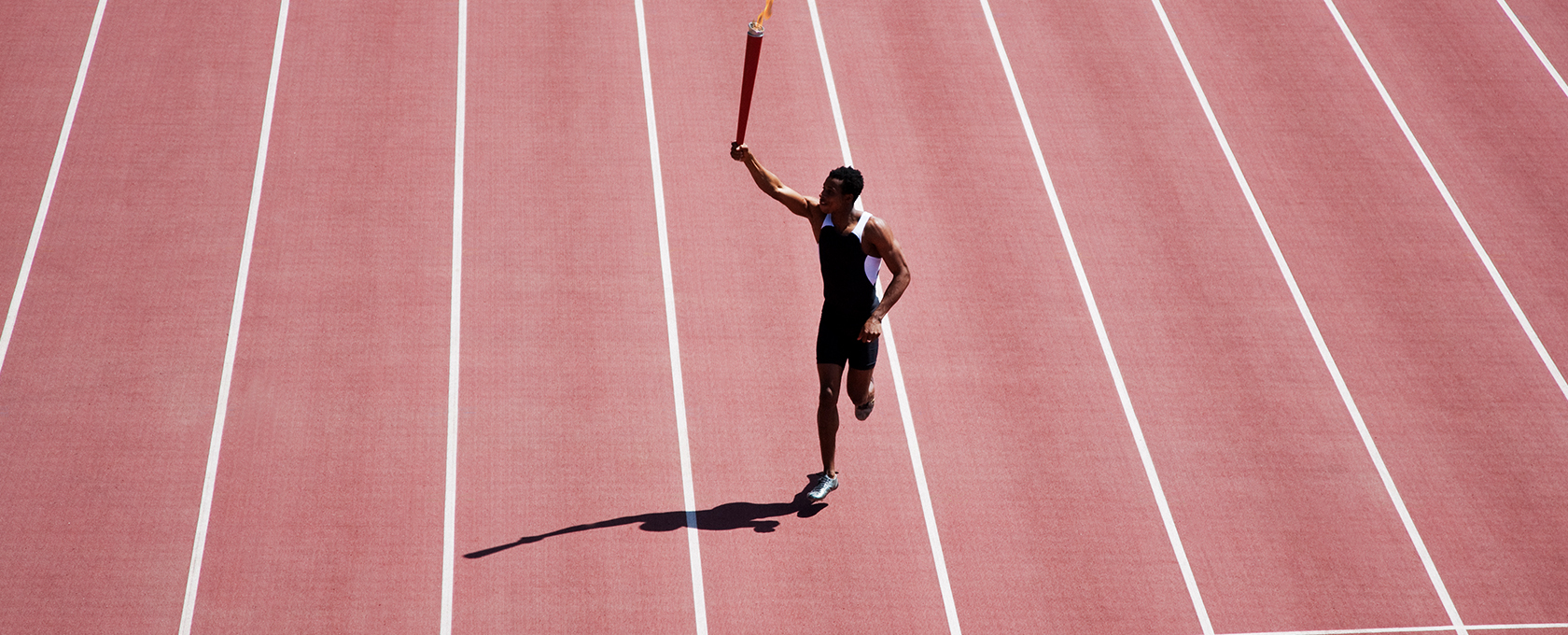 Athlete running on a red track holding a torch aloft, casting a shadow, with empty lanes on either side—symbolizing the determination found in top lawyers in Chicago.
