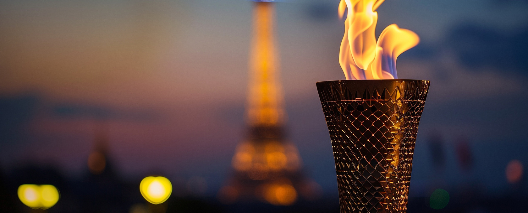 A lit Olympic-style torch is in focus with the Eiffel Tower blurred in the background at dusk, symbolizing the dedication and perseverance found at top law offices or among lawyers in Chicago.