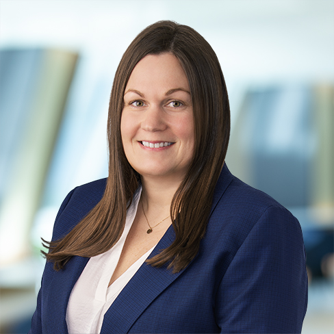 A woman in a blue blazer and white blouse smiles at the camera in a brightly lit office, reflecting the professionalism of top lawyers in Chicago.