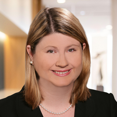 A woman with shoulder-length blonde hair, wearing a black blazer, pearl necklace, and pearl earrings, smiles in a well-lit corporate law office—reflecting the professionalism of Chicago lawyers.