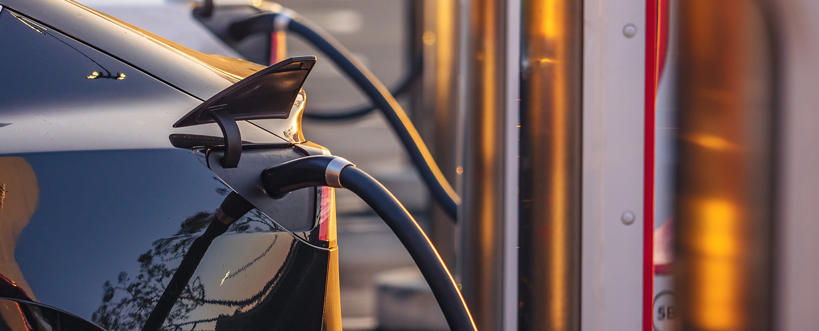 An electric car is plugged into a charging station, sunlight reflecting off the vehicle and charger—just outside a busy office of Chicago lawyers specializing in intellectual property law.