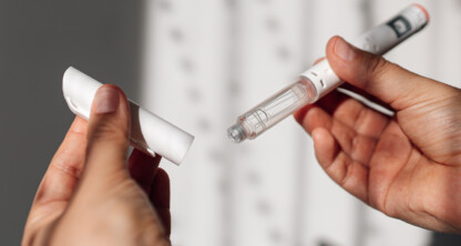 A person holds an insulin pen in one hand and removes the cap with the other hand, illustrating precision and care much like chicago lawyers handle complex litigation support.