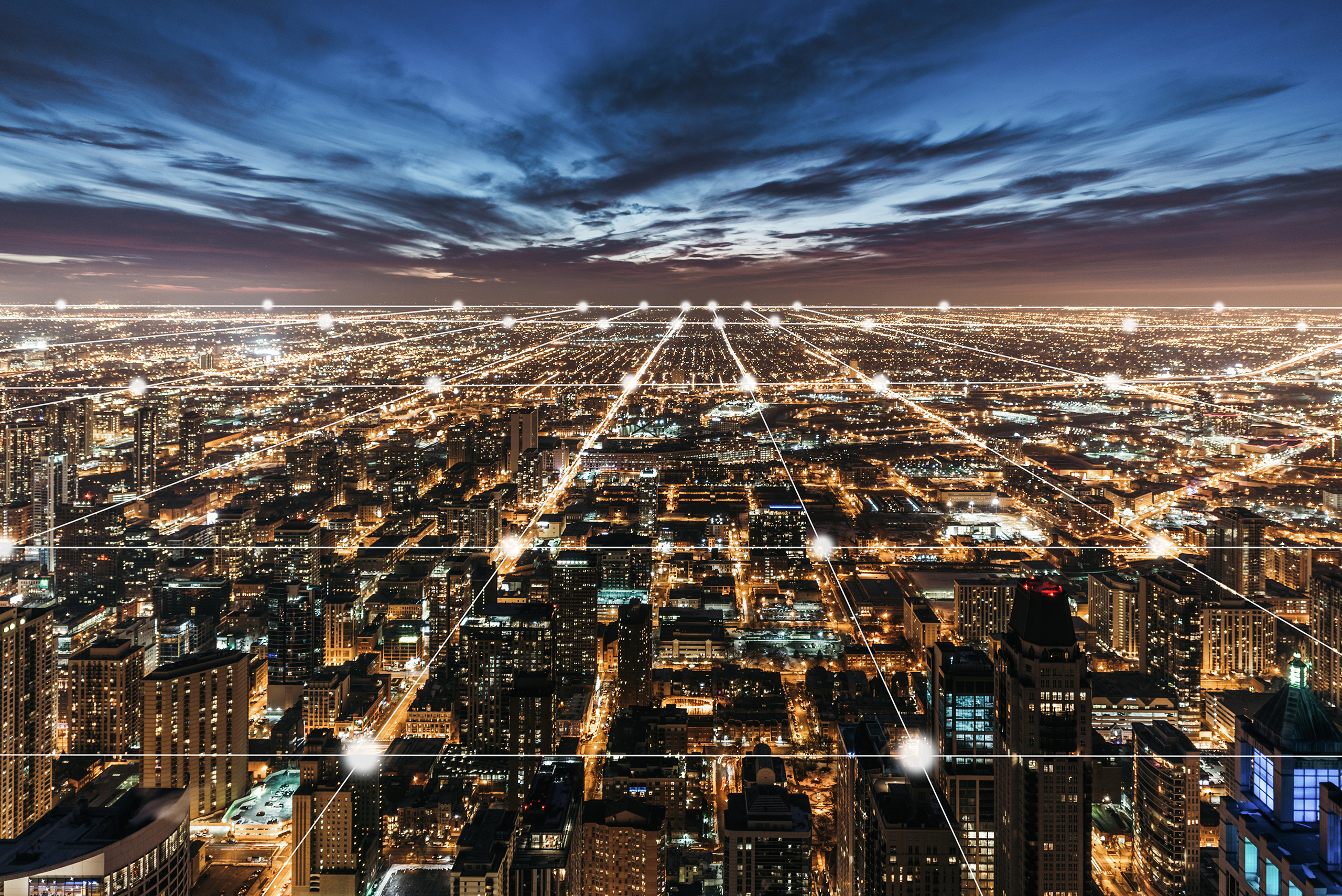 Aerial view of a city at night with illuminated grid-like streets and buildings under a cloudy sky, lines and dots digitally added to emphasize the city grid layout, reflecting the structured precision found in top law offices.