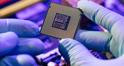 A person wearing blue gloves holds a computer processor chip above a motherboard, highlighting its gold contacts and detailed circuitry—reflecting the precision found in litigation support for lawyers in Chicago.